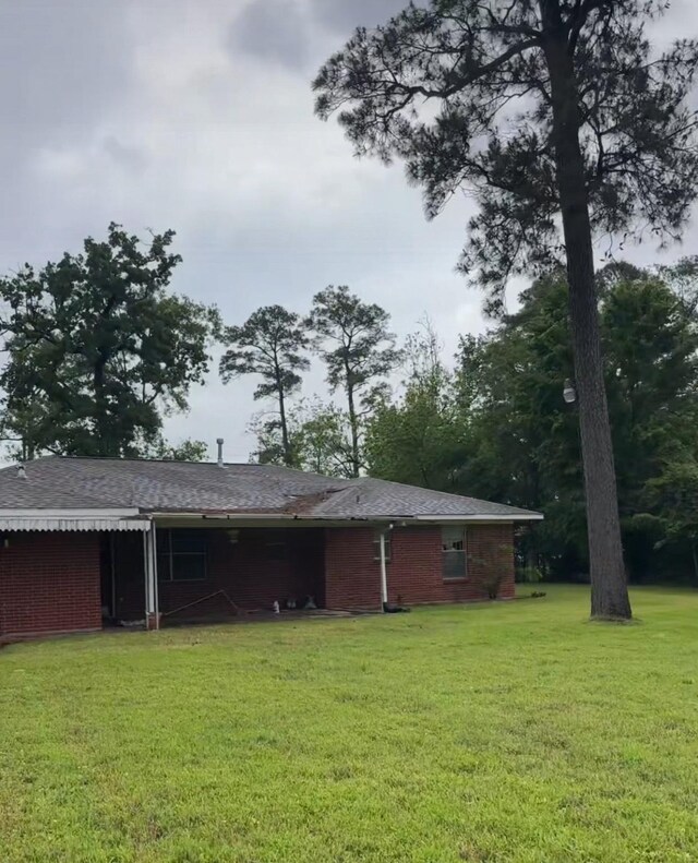 12420 Wallisville Rd, Houston, TX 77013 - rear view of property with a yard, brick siding, and roof with shingles