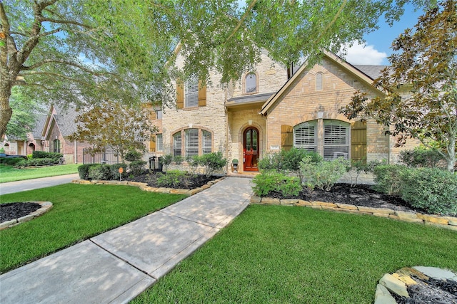 5714 Spring River Ln, Fulshear, TX 77441 - tudor-style house featuring a front yard, stone siding, and brick siding