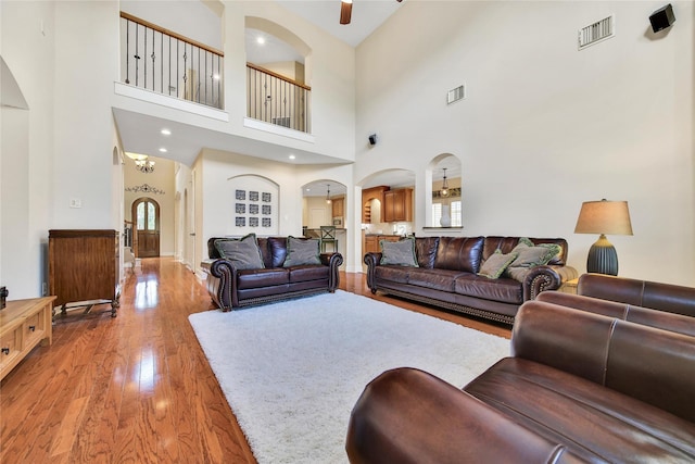 5714 Spring River Ln, Fulshear, TX 77441 - living room featuring arched walkways, wood finished floors, a towering ceiling, and a ceiling fan