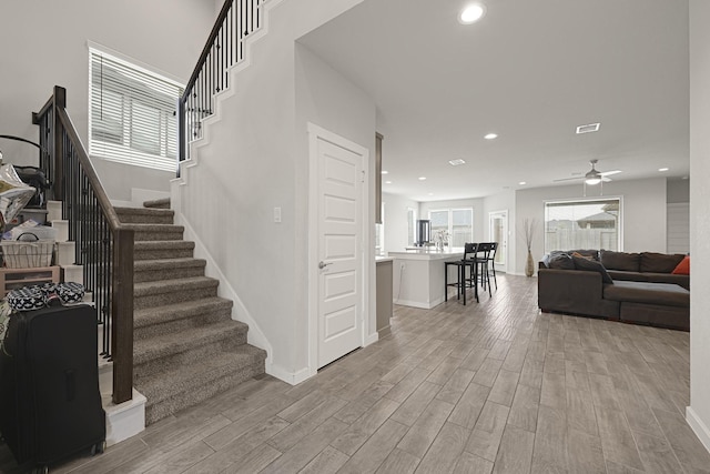 stairway with wood finished floors, recessed lighting, ceiling fan, and baseboards