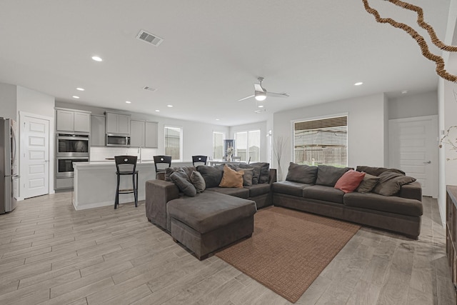 living room featuring ceiling fan, light wood-type flooring, and recessed lighting
