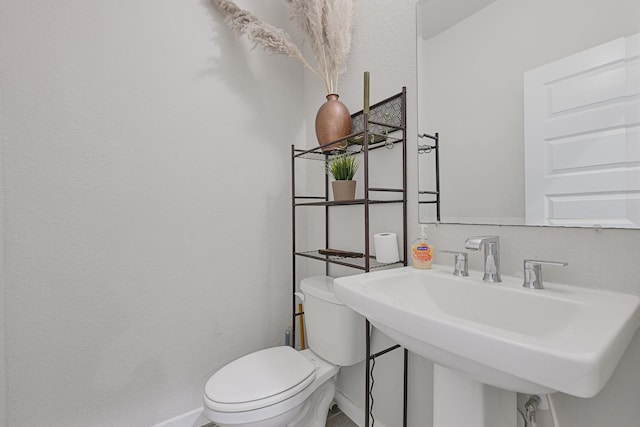 bathroom with baseboards, a sink, and toilet