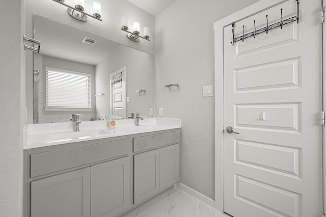 bathroom featuring marble look tile flooring, baseboards, and double vanity