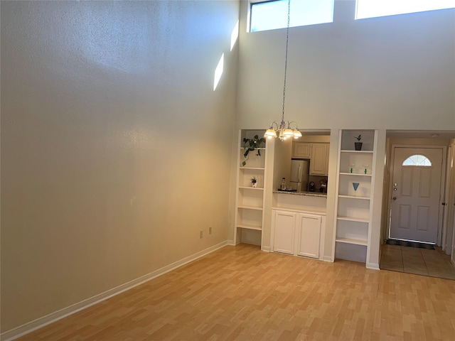 10075 Westpark Dr Unit 43, Houston, TX 77042 - unfurnished living room featuring light wood-type flooring, a high ceiling, baseboards, and a chandelier