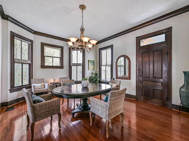 1515 24th St, Galveston, TX 77550 - dining area with crown molding, a chandelier, dark wood finished floors, and baseboards