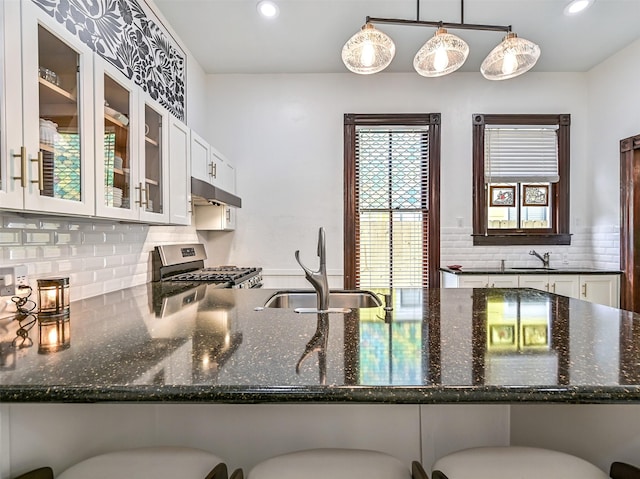 1515 24th St, Galveston, TX 77550 - kitchen with stainless steel range with gas stovetop, a sink, under cabinet range hood, dark stone counters, and recessed lighting