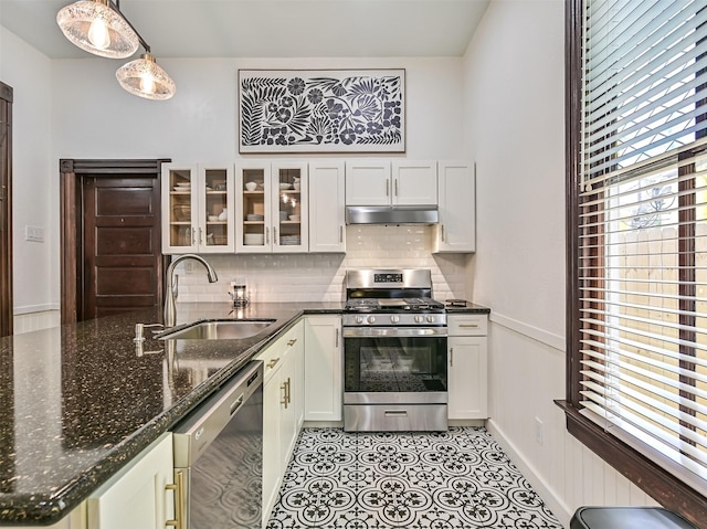 1515 24th St, Galveston, TX 77550 - kitchen with appliances with stainless steel finishes, a sink, under cabinet range hood, decorative backsplash, and glass insert cabinets
