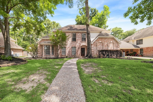 view of front of home featuring a front yard, brick siding, and roof with shingles