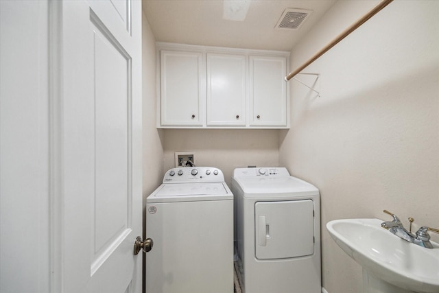 washroom featuring independent washer and dryer and cabinet space