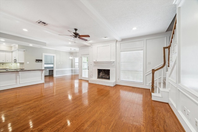 unfurnished living room featuring a ceiling fan, stairway, a fireplace, light wood-type flooring, and recessed lighting