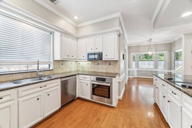 kitchen featuring black appliances, a sink, white cabinets, light wood-style flooring, and tasteful backsplash