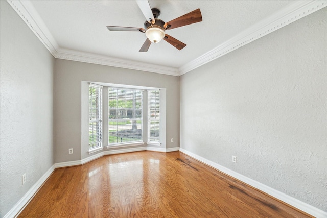 unfurnished room with wood finished floors, baseboards, ornamental molding, ceiling fan, and a textured wall