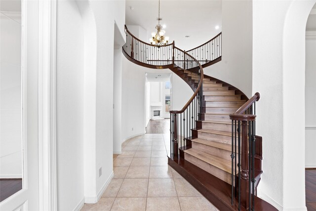 17803 Paint Bluff Ln, Cypress, TX 77433 - stairs featuring arched walkways, tile patterned floors, a chandelier, baseboards, and a towering ceiling