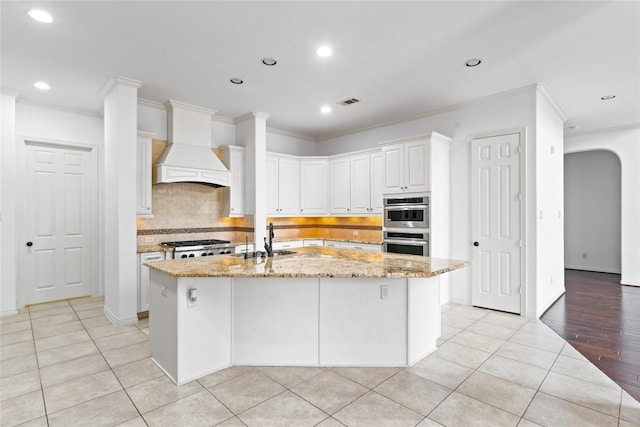 17803 Paint Bluff Ln, Cypress, TX 77433 - kitchen featuring custom range hood, recessed lighting, a center island with sink, light stone countertops, and backsplash