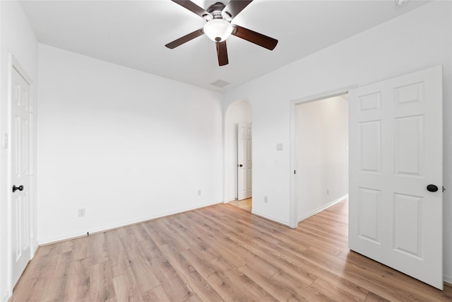 17803 Paint Bluff Ln, Cypress, TX 77433 - unfurnished bedroom featuring light wood-style flooring, arched walkways, ceiling fan, and baseboards