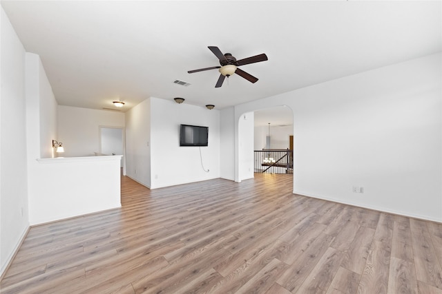 17803 Paint Bluff Ln, Cypress, TX 77433 - unfurnished living room with a ceiling fan, light wood-style flooring, arched walkways, and baseboards