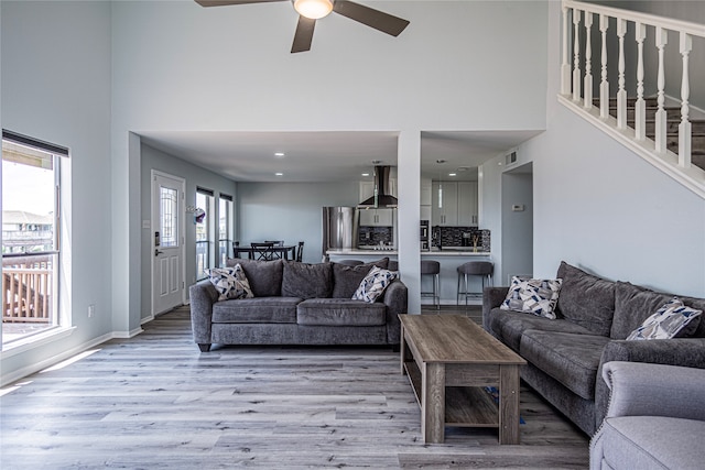 301 Commander Dr, Tiki Island, TX 77554 - living room with light wood finished floors, a high ceiling, ceiling fan, baseboards, and stairway