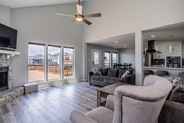 301 Commander Dr, Tiki Island, TX 77554 - living room with wood finished floors, ceiling fan, a stone fireplace, high vaulted ceiling, and recessed lighting