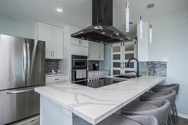 301 Commander Dr, Tiki Island, TX 77554 - kitchen featuring freestanding refrigerator, wall chimney range hood, double oven, a sink, and a peninsula