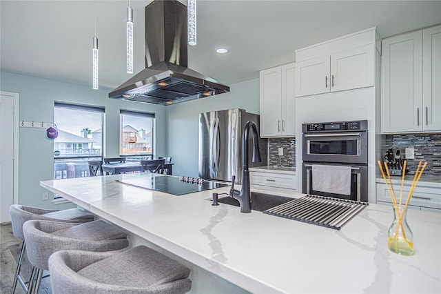 301 Commander Dr, Tiki Island, TX 77554 - kitchen featuring island range hood, double oven, black electric stovetop, freestanding refrigerator, and tasteful backsplash