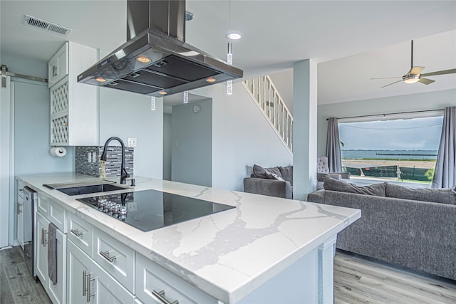 301 Commander Dr, Tiki Island, TX 77554 - kitchen with island exhaust hood, black electric cooktop, open floor plan, a sink, and light wood-style flooring