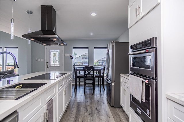 301 Commander Dr, Tiki Island, TX 77554 - kitchen featuring island exhaust hood, appliances with stainless steel finishes, a sink, light wood-type flooring, and white cabinetry