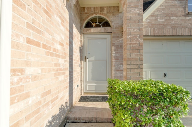 entrance to property featuring brick siding and a garage