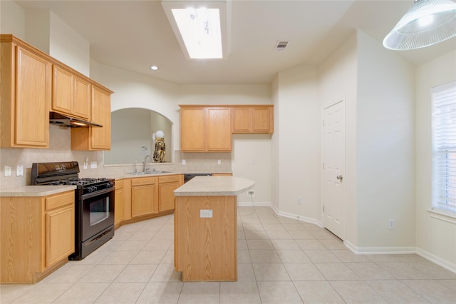 kitchen featuring black range with gas stovetop, a sink, a center island, decorative backsplash, and light countertops