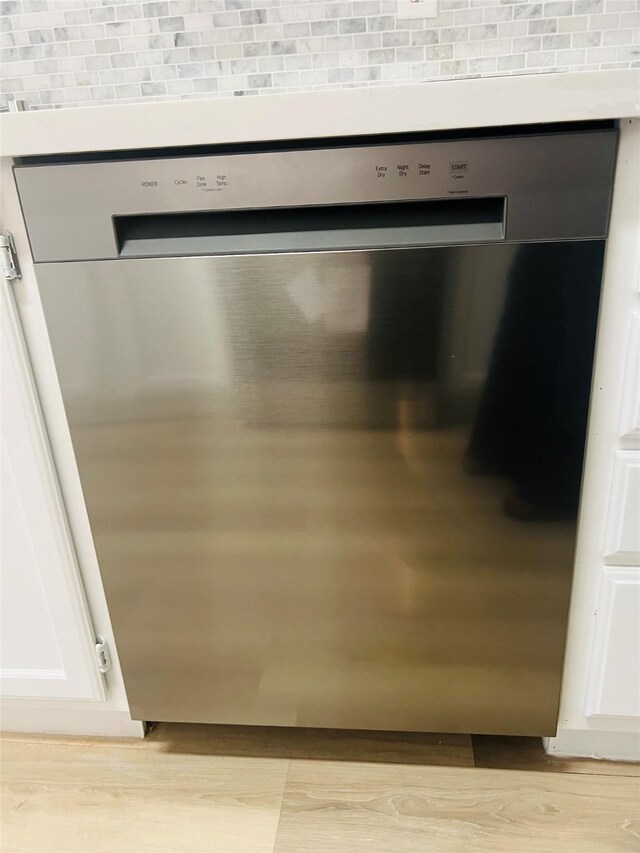 2668 Bering Dr Unit 2668, Houston, TX 77057 - kitchen view of stainless steel dishwasher, light wood-style flooring, decorative backsplash, and white cabinetry