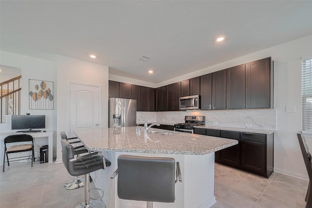 6831 Beck Canyon Dr, Houston, TX 77084 - kitchen featuring stainless steel appliances, a sink, a breakfast bar, tasteful backsplash, and a kitchen island with sink