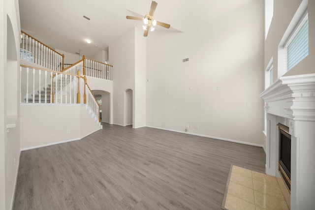 18231 Emerald Stone Ln, Houston, TX 77094 - unfurnished living room featuring a high ceiling, a ceiling fan, wood finished floors, a fireplace, and stairs
