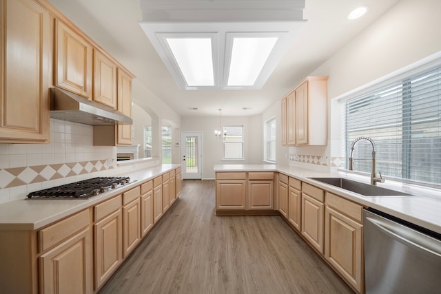 18231 Emerald Stone Ln, Houston, TX 77094 - kitchen featuring light brown cabinetry, appliances with stainless steel finishes, a sink, light wood-style floors, and a peninsula