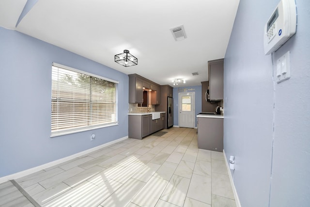 2323 Chalet Rd, Houston, TX 77038 - kitchen with light countertops, stainless steel fridge with ice dispenser, baseboards, dark brown cabinets, and backsplash