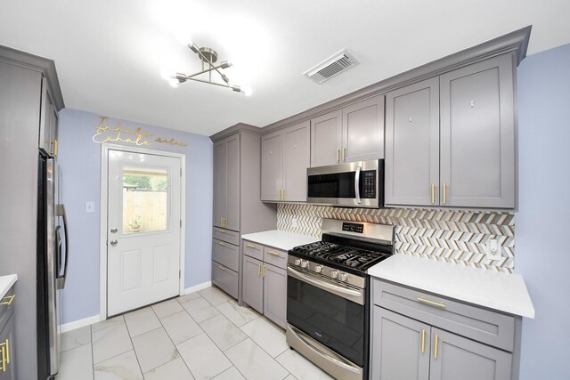 2323 Chalet Rd, Houston, TX 77038 - kitchen featuring appliances with stainless steel finishes, gray cabinetry, and tasteful backsplash