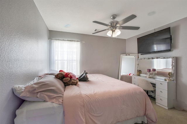 bedroom with light colored carpet, ceiling fan, and a textured wall