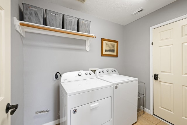12002 Iris Canyon Dr, Tomball, TX 77377 - laundry room with washing machine and dryer, light tile patterned floors, baseboards, and a textured ceiling
