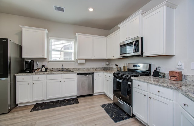 3121 Freeboard Dr, Texas City, TX 77510 - kitchen with appliances with stainless steel finishes, a sink, white cabinets, light wood-style flooring, and light stone countertops