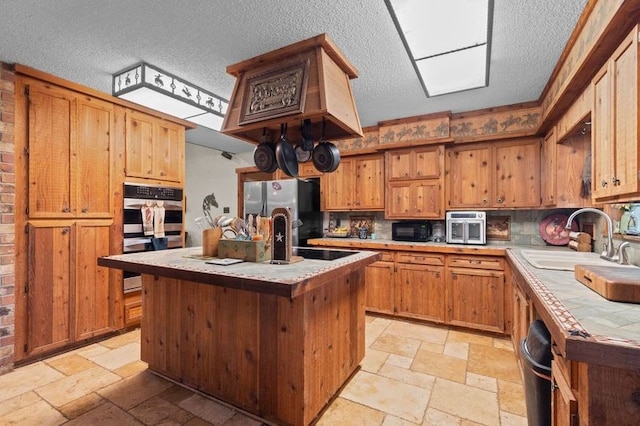 1816 County Road 936b, Alvin, TX 77511 - kitchen featuring appliances with stainless steel finishes, stone tile flooring, a textured ceiling, a sink, and tile counters
