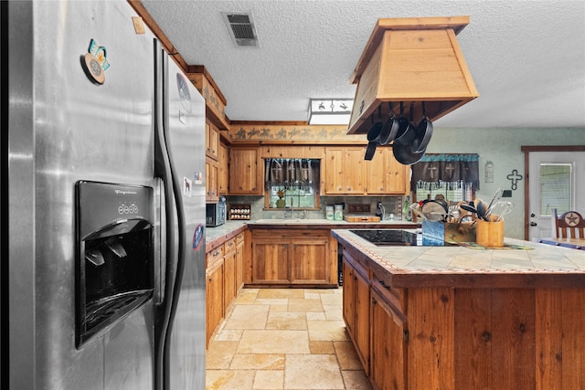 1816 County Road 936b, Alvin, TX 77511 - kitchen featuring stainless steel refrigerator with ice dispenser, tile countertops, stone tile flooring, a textured ceiling, and brown cabinetry