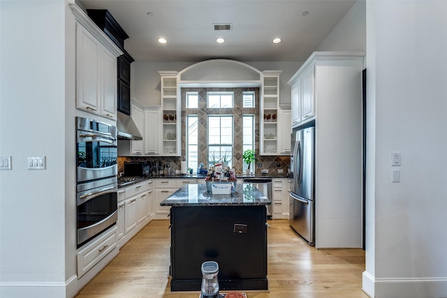 1652 Norfolk St Unit A, Houston, TX 77006 - kitchen with appliances with stainless steel finishes, open shelves, dark stone countertops, a center island, and tasteful backsplash