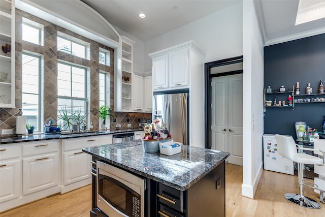 1652 Norfolk St Unit A, Houston, TX 77006 - kitchen with appliances with stainless steel finishes, a sink, tasteful backsplash, white cabinetry, and glass insert cabinets