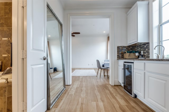 1652 Norfolk St Unit A, Houston, TX 77006 - kitchen with beverage cooler, white cabinets, a sink, decorative backsplash, and ornamental molding