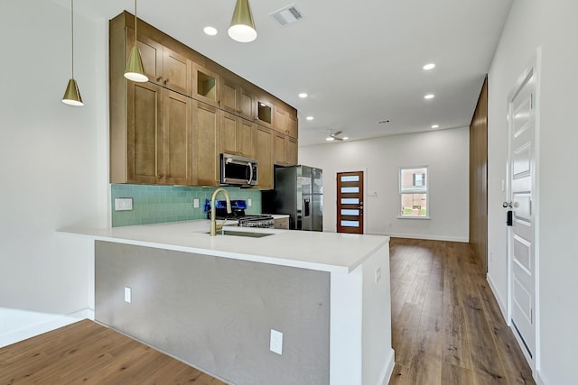 5731 Belvedere St, Houston, TX 77021 - kitchen featuring stainless steel appliances, a sink, backsplash, wood finished floors, and light countertops