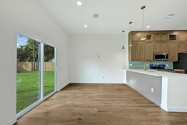 5731 Belvedere St, Houston, TX 77021 - kitchen with stainless steel microwave, stove, a sink, freestanding refrigerator, and light wood-type flooring