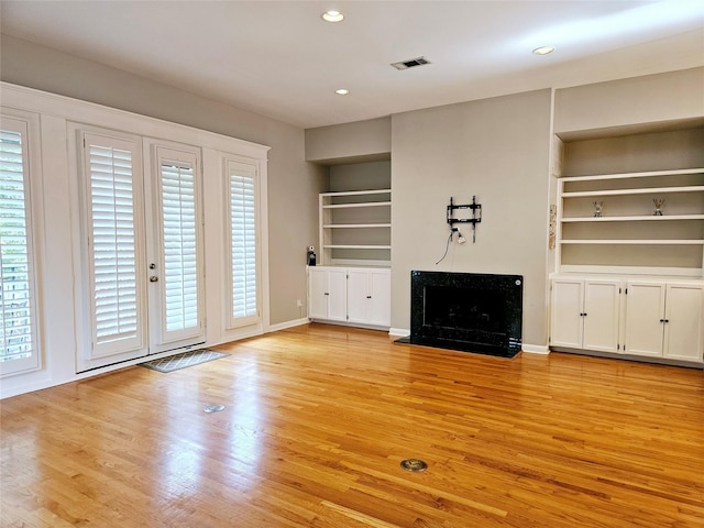 3818 Hazard St, Houston, TX 77098 - unfurnished living room with built in features, light wood-type flooring, a premium fireplace, and recessed lighting