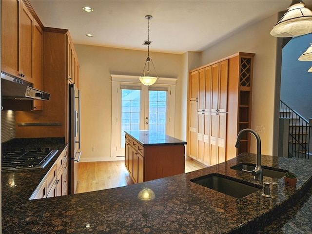3818 Hazard St, Houston, TX 77098 - kitchen featuring a sink, stainless steel gas stovetop, light wood finished floors, under cabinet range hood, and a center island