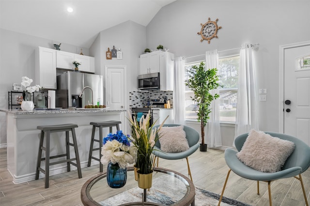 16858 W Alderson, Montgomery, TX 77316 - kitchen featuring appliances with stainless steel finishes, white cabinets, decorative backsplash, a kitchen bar, and light wood-style floors