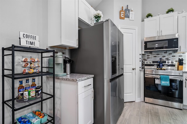 16858 W Alderson, Montgomery, TX 77316 - kitchen with appliances with stainless steel finishes, white cabinetry, decorative backsplash, light stone counters, and light wood-type flooring