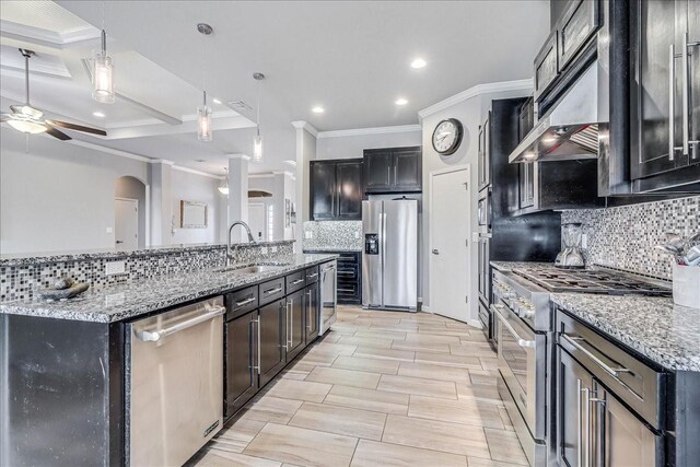 kitchen featuring stainless steel appliances, a sink, ceiling fan, crown molding, and tasteful backsplash