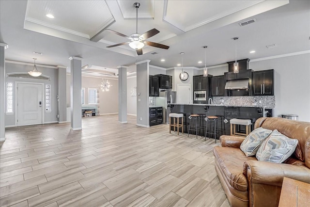living room with decorative columns, a ceiling fan, coffered ceiling, crown molding, and recessed lighting